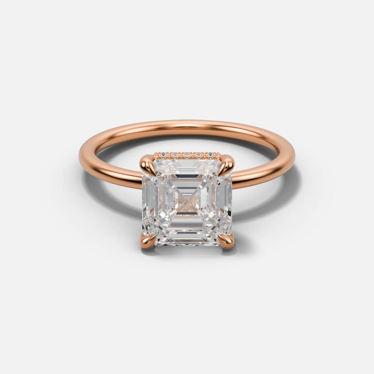 Rose gold Asscher-cut solitaire tilted back to show the stone face and the fine row of hidden halo diamonds beneath it