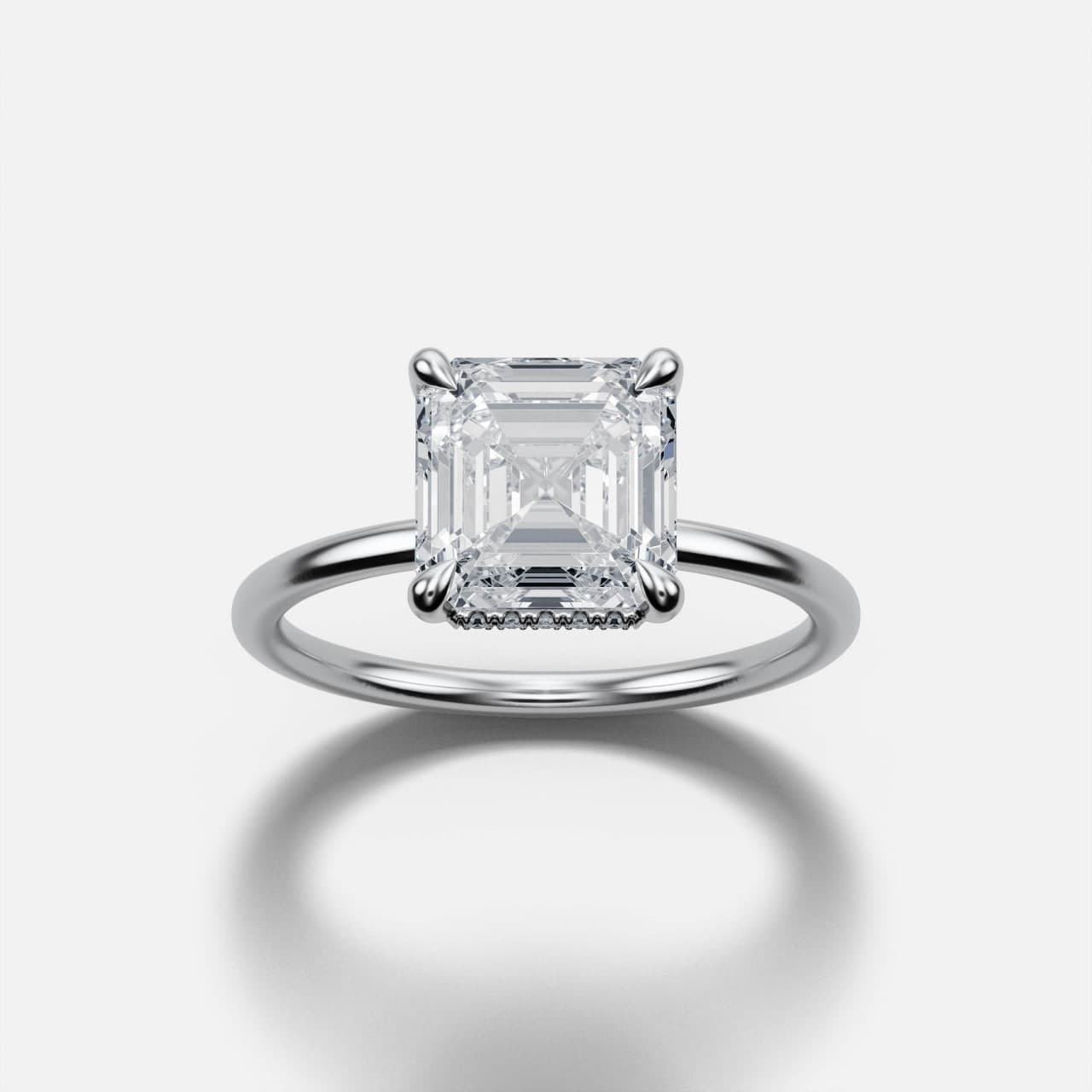 White gold Asscher-cut diamond solitaire viewed head-on, square step-cut stone held in four single claws