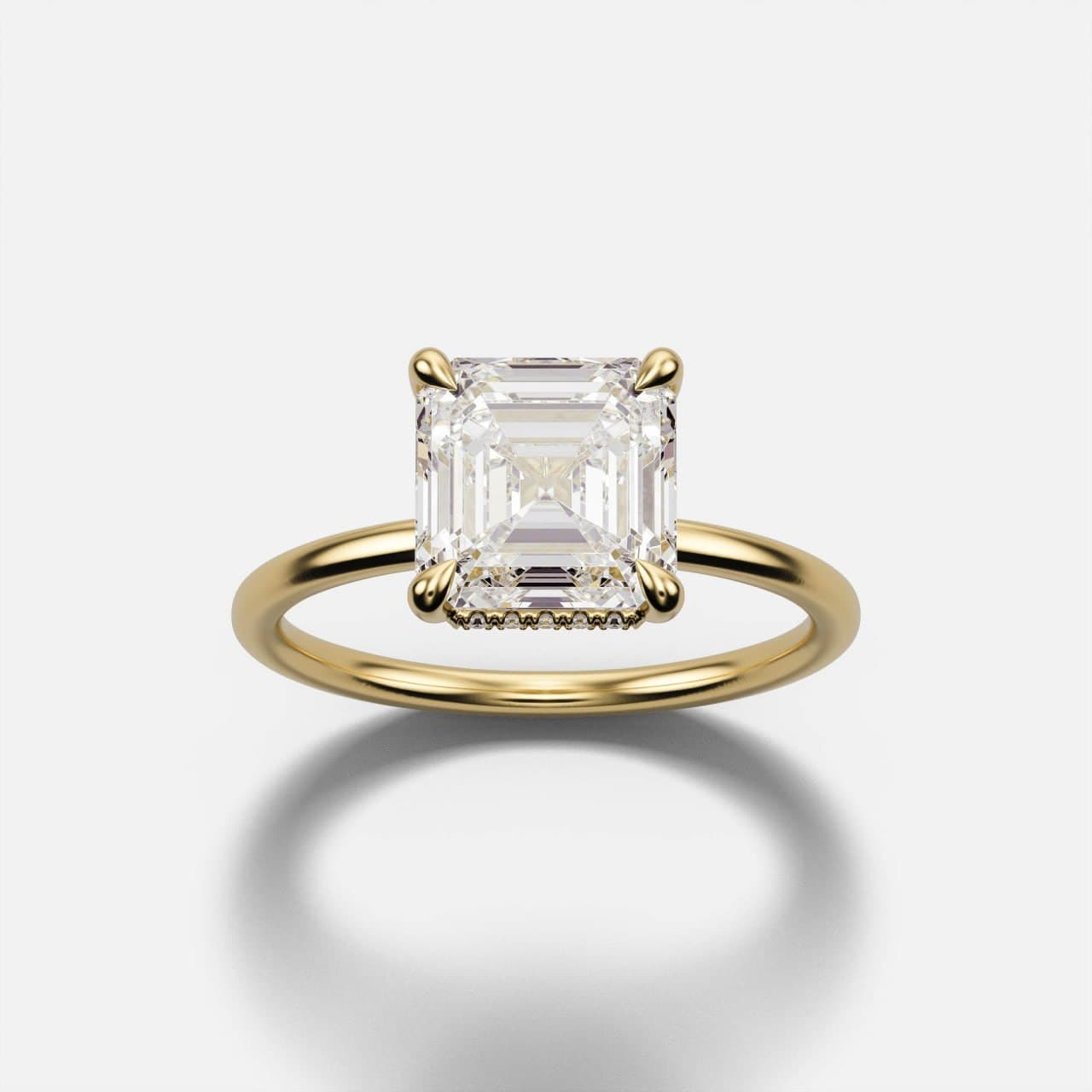 Yellow gold Asscher-cut diamond solitaire viewed head-on, square step cut with cropped corners in four tapered claws