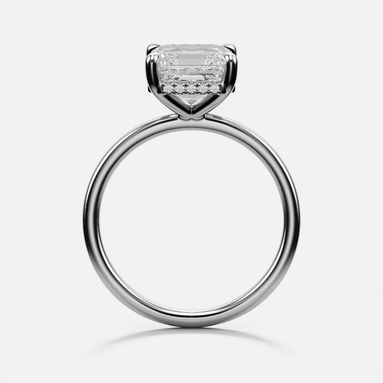 Profile view of a white gold emerald-cut solitaire engagement ring with a hidden halo of pavé diamonds under the centre stone