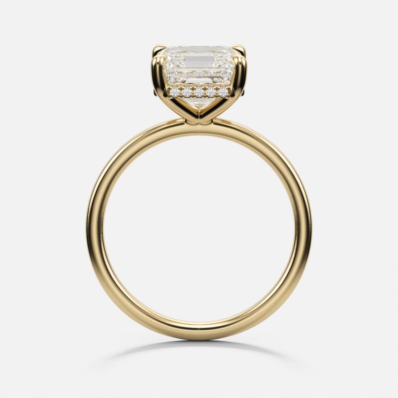 Profile view of a yellow gold emerald-cut solitaire engagement ring with a hidden halo of small diamonds beneath the centre stone