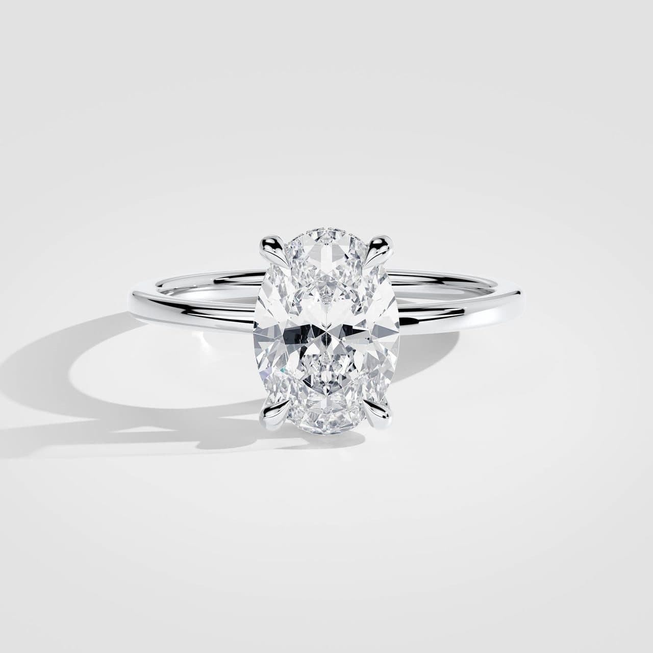 White gold oval diamond solitaire from above under neutral studio light, the metal cool white and the diamond bright and colourless